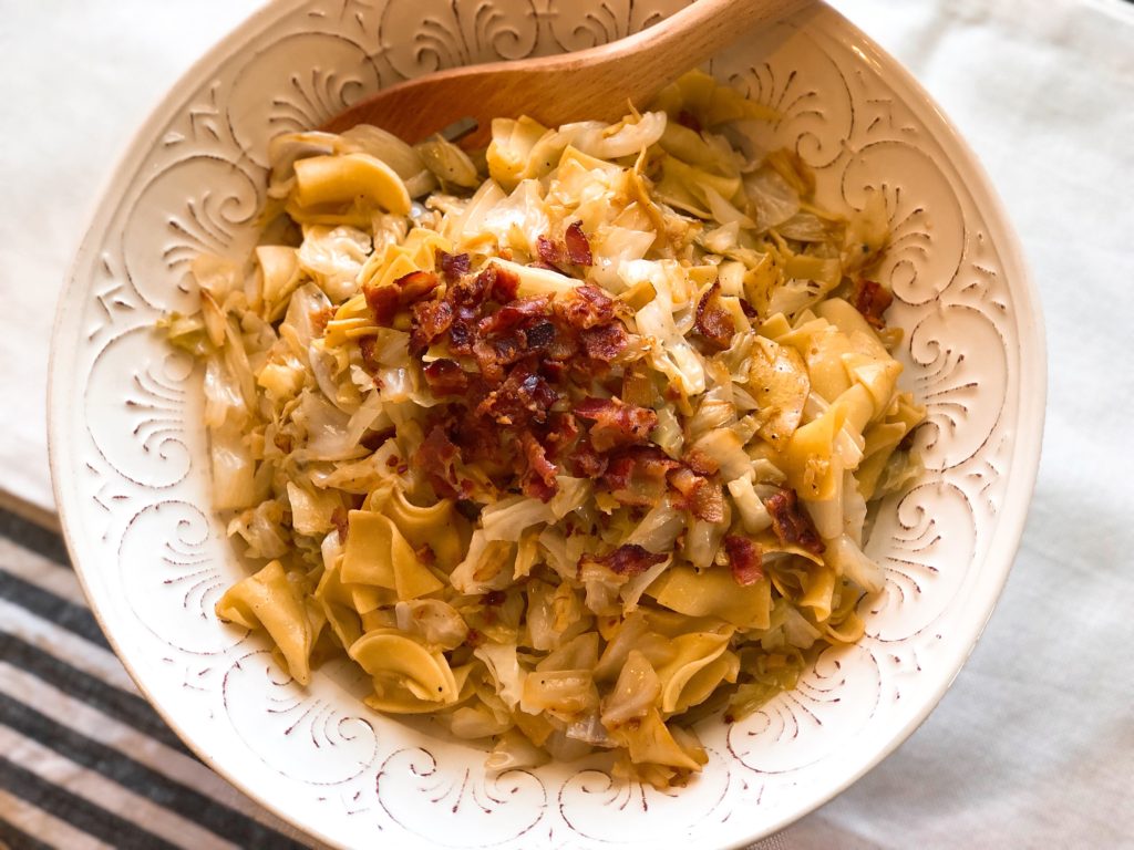 Fried Cabbage and Noodles in a white serving bowl with a wooden spoon