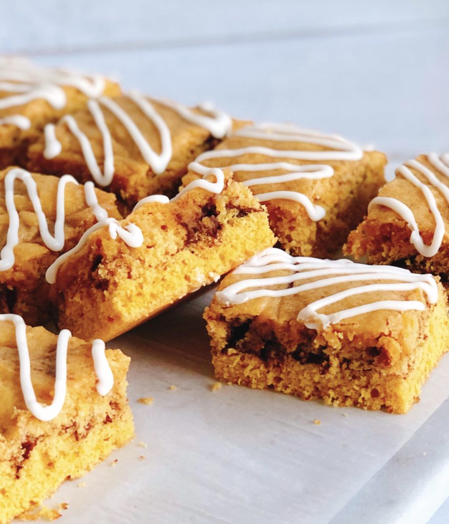Pumpkin Snickerdoodle Bars with Icing Drizzle laying on a marble board. One bar stacked on another.