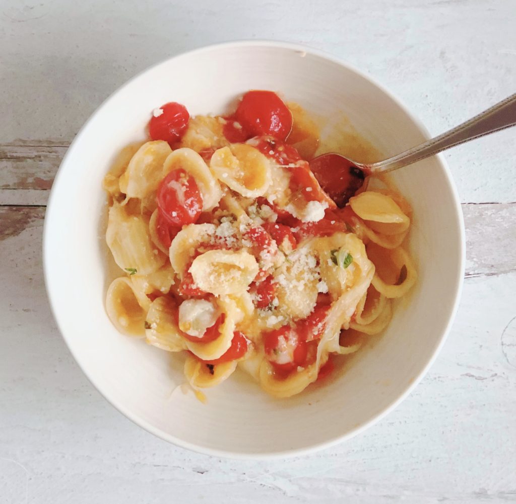Tomato and Garlic Orecchiette in a white bowl with spoon.