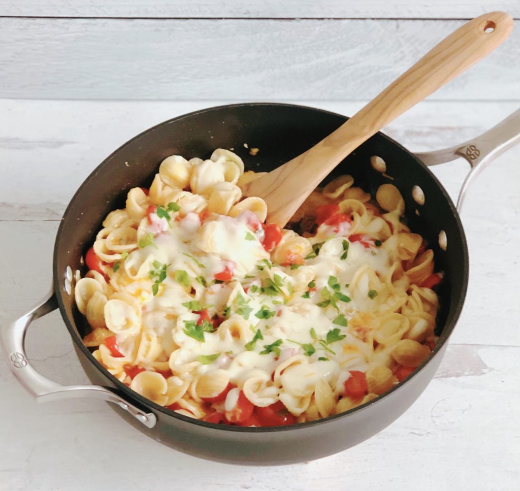 Tomato and Garlic Orecchiette in a skillet with wooden spoon.