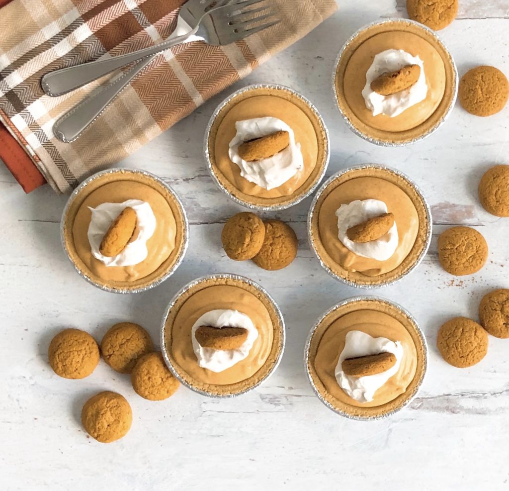 Top view of Mini Pumpkin Mousse Pies topped with gingersnaps and surrounded by gingersnaps on the table.