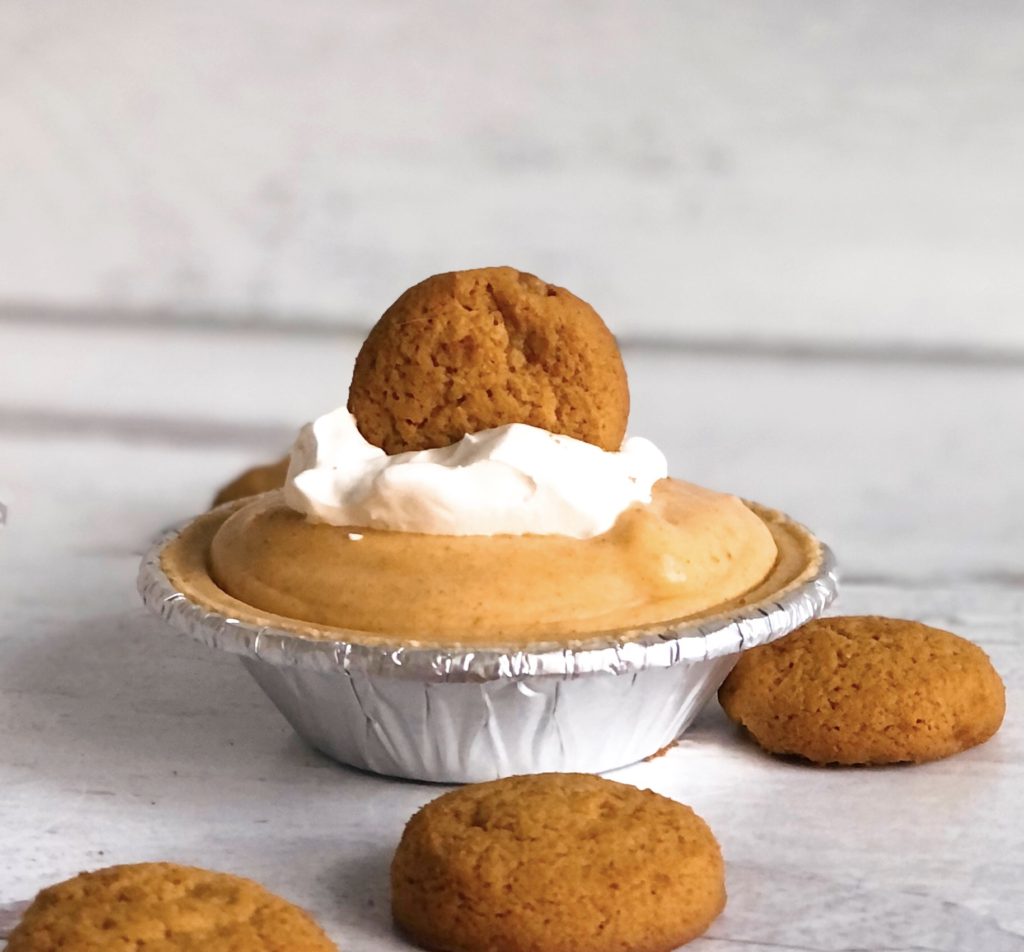 Mini Pumpkin Mousse Pie with Gingersnap on top and surrounded by gingersnaps.