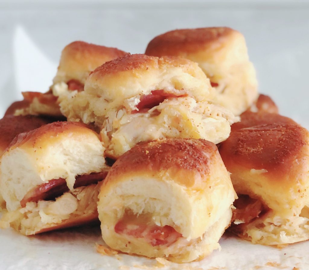 Stacks of melty Turkey Bacon Brie Sliders on a counter.