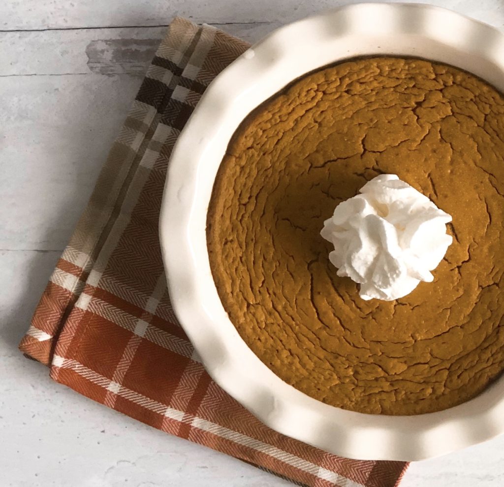 Crustless Pumpkin Pie in a white pie plate sitting on a plaid napkin.