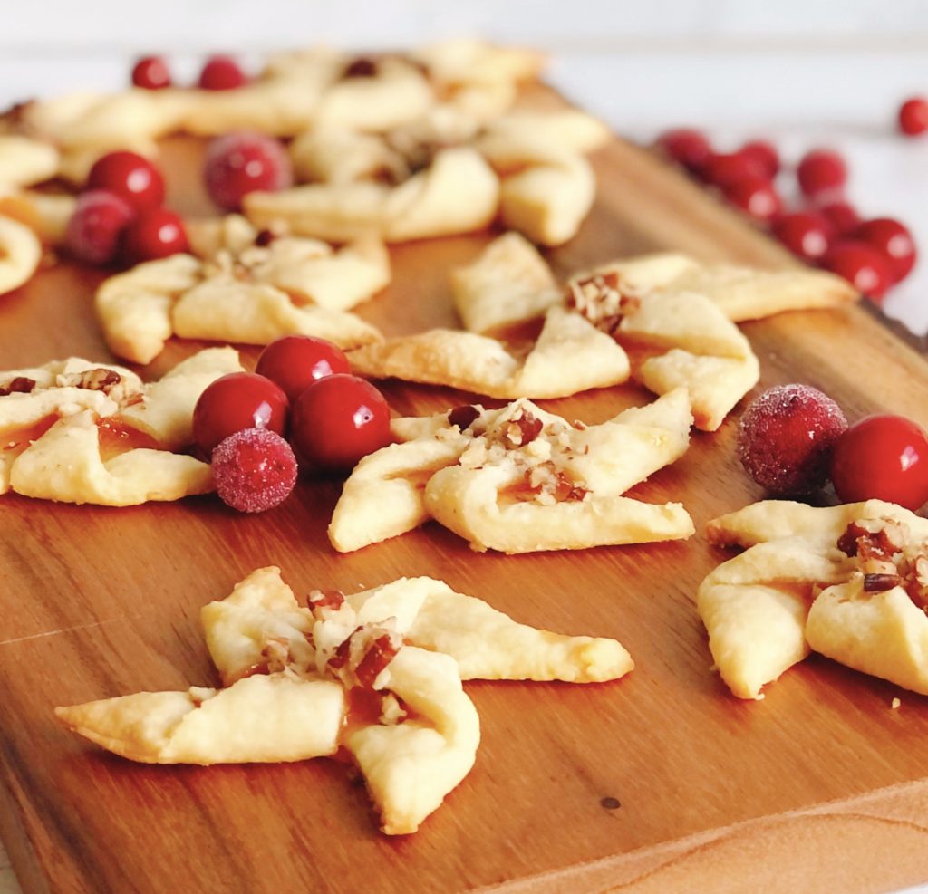 Cream Cheese Pinwheels on wooden board surrounded by sugared cranberries.