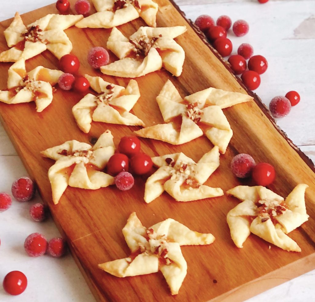Cream Cheese Pinwheels on wooden board surrounded by sugared cranberries.