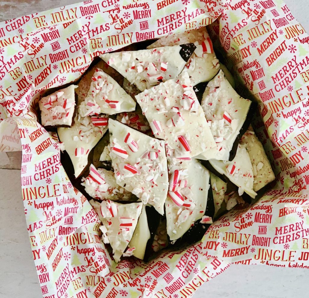 Peppermint Bark in tin with holiday parchment paper.