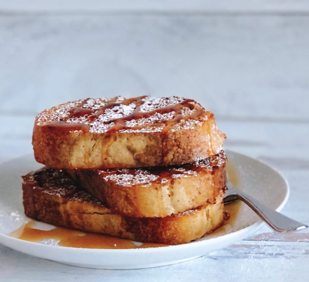 Sheet Pan French Toast stacked on a plate topped with maple syrup.