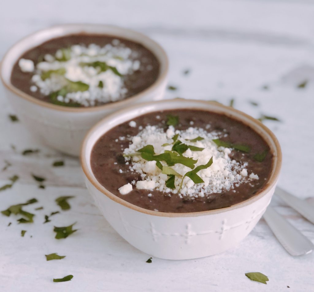 Vegetarian Black Bean Soup topped with cheese and spoons on the side
