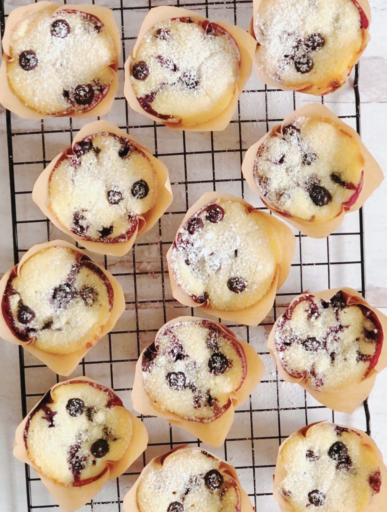 Blueberry Ricotta Muffins on a wire cooling rack sprinkled with powdered sugar