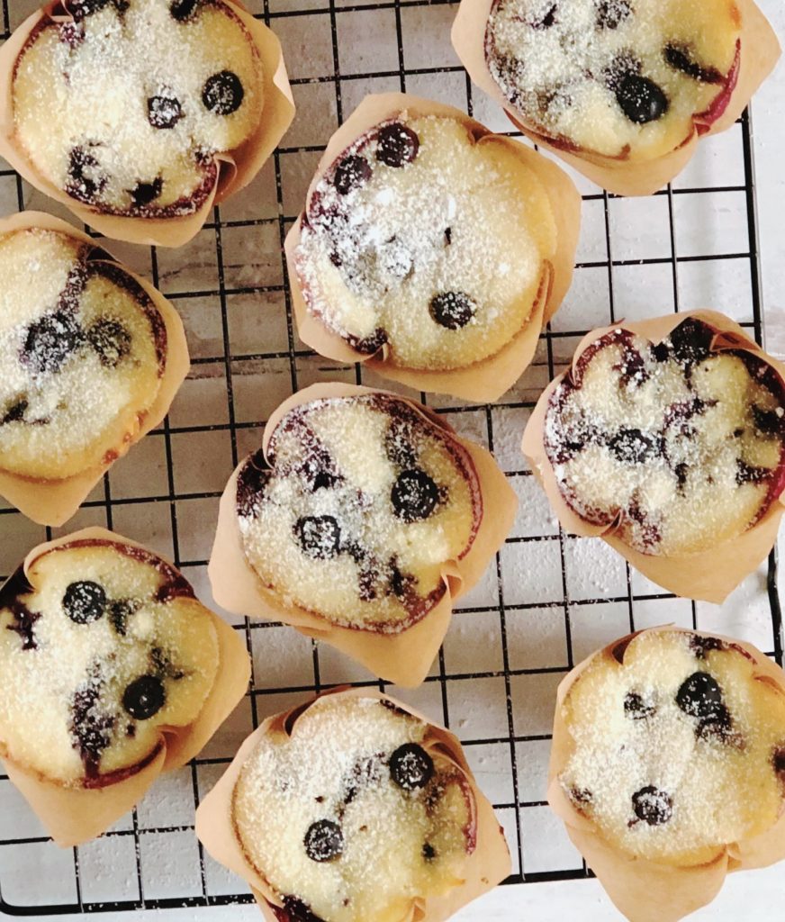 Blueberry Ricotta Muffins on a wire cooling rack sprinkled with powdered sugar