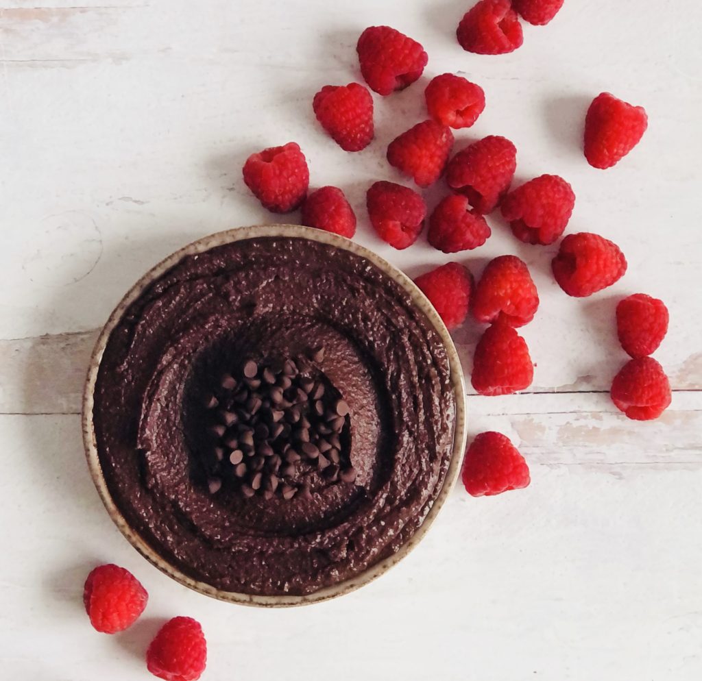 Dark Chocolate Hummus topped with chocolate chips and surrounded by raspberries.