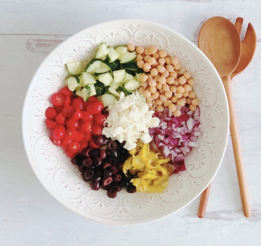 Greek Orzo Salad in a white bowl with wooden salad spoons