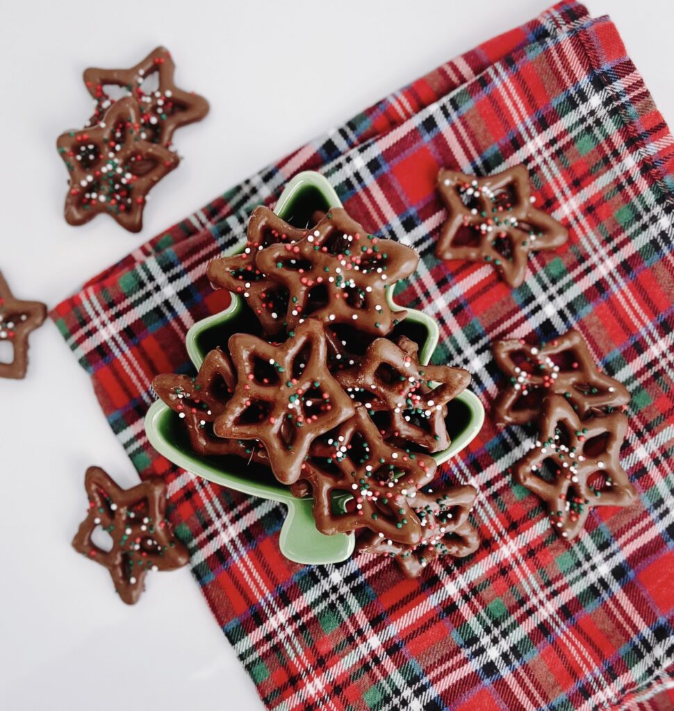Chocolate Covered Pretzels in a Christmas Tree bowl sitting on a Christmas plaid napkin