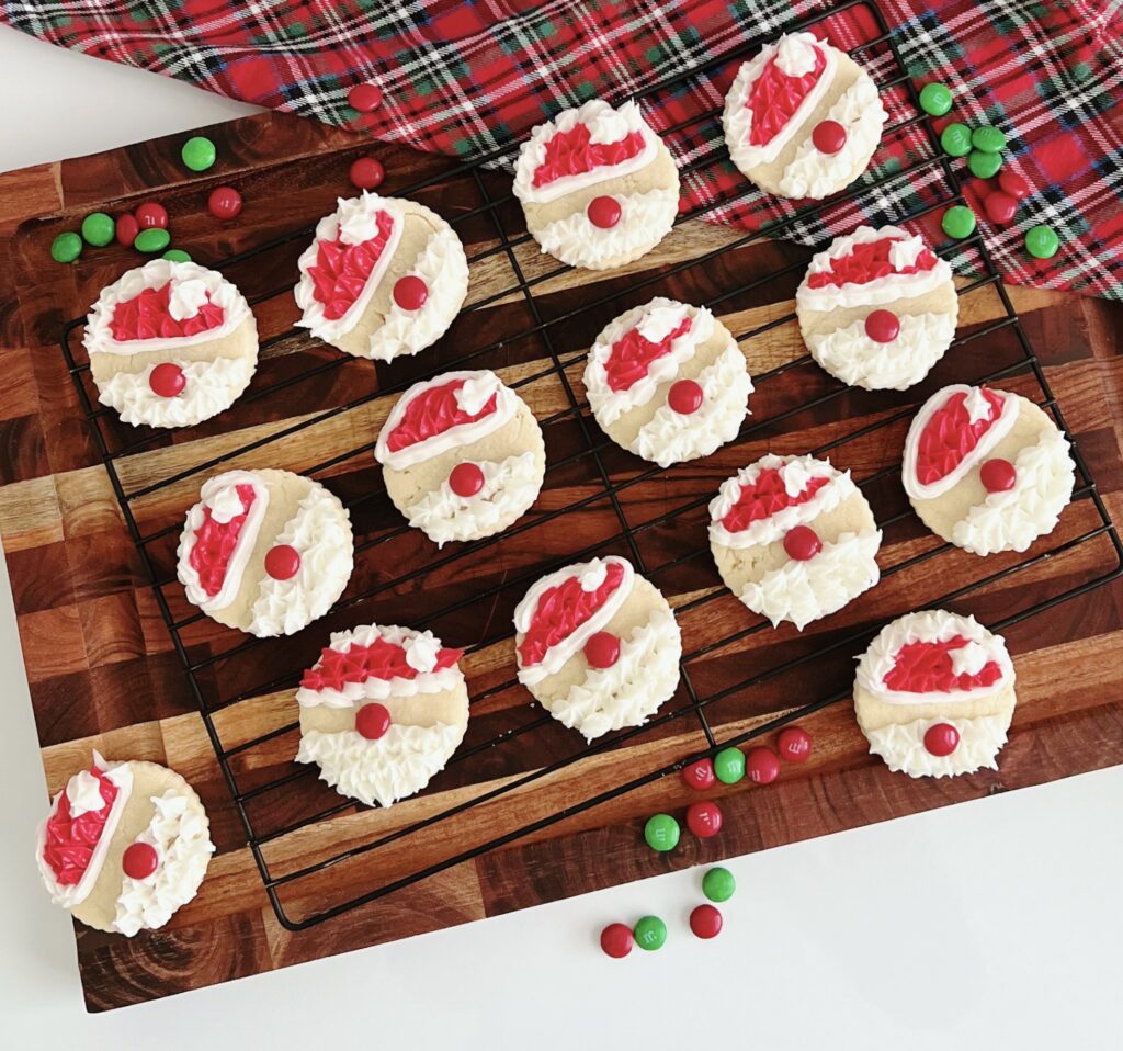 Shortbread Santas on a wire rack on top of a wooden cutting board