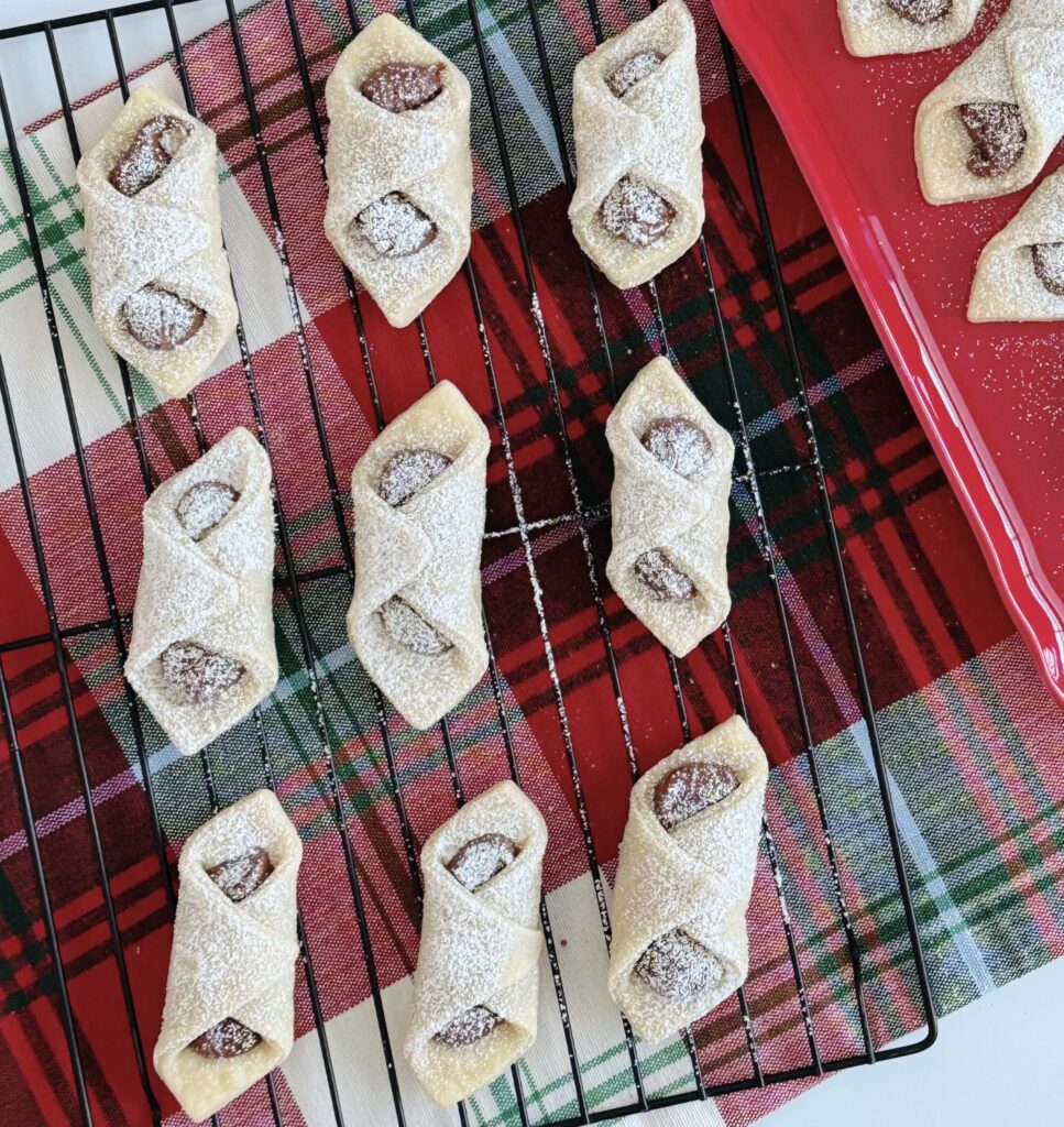 Italian Pinch Cookies on a wire rack on top of a plain tablecloth.